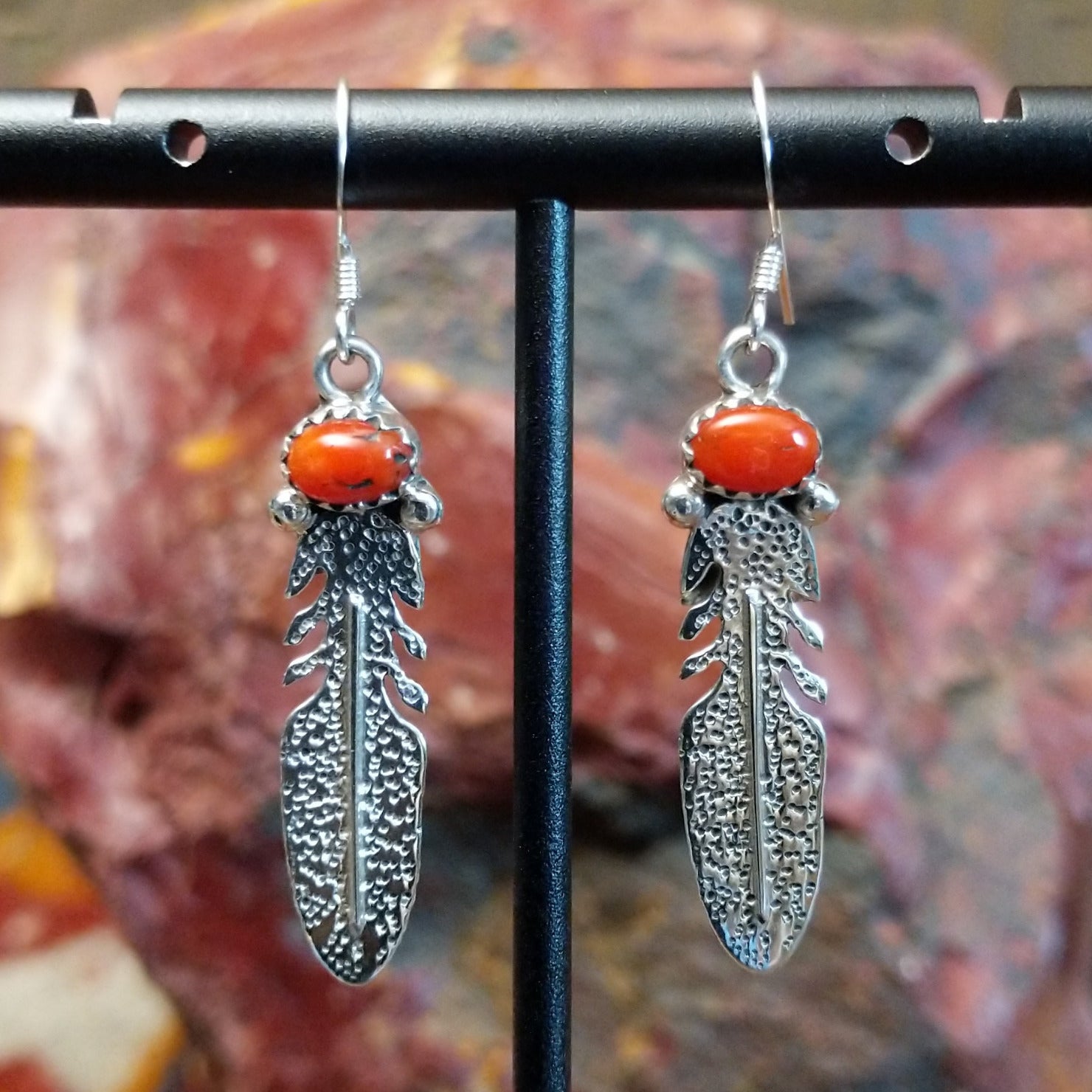 Sterling silver dangle feather earrings with coral set in notched bezels.