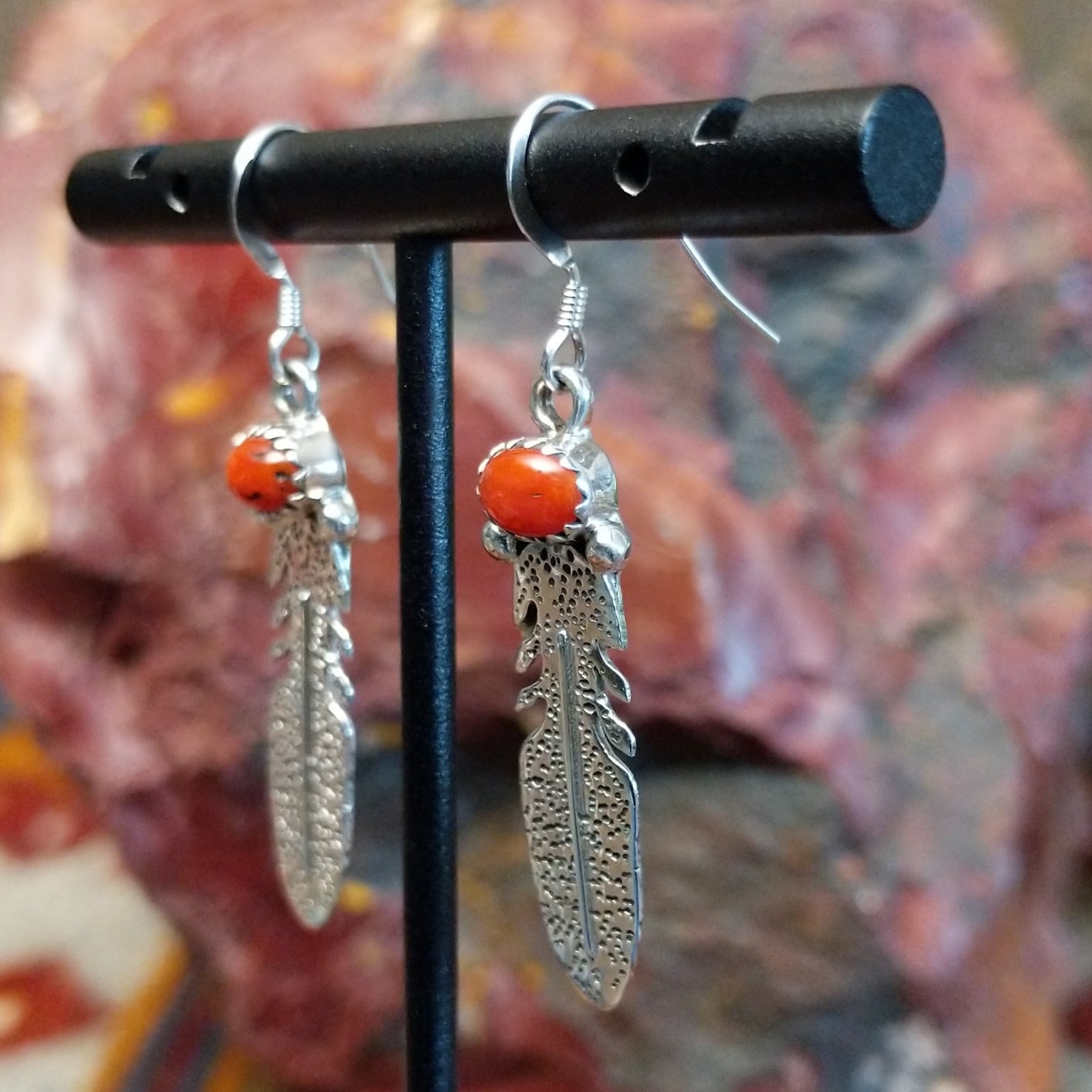 Sterling silver dangle feather earrings with coral set in notched bezels.