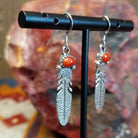 Sterling silver dangle feather earrings with coral set in notched bezels.