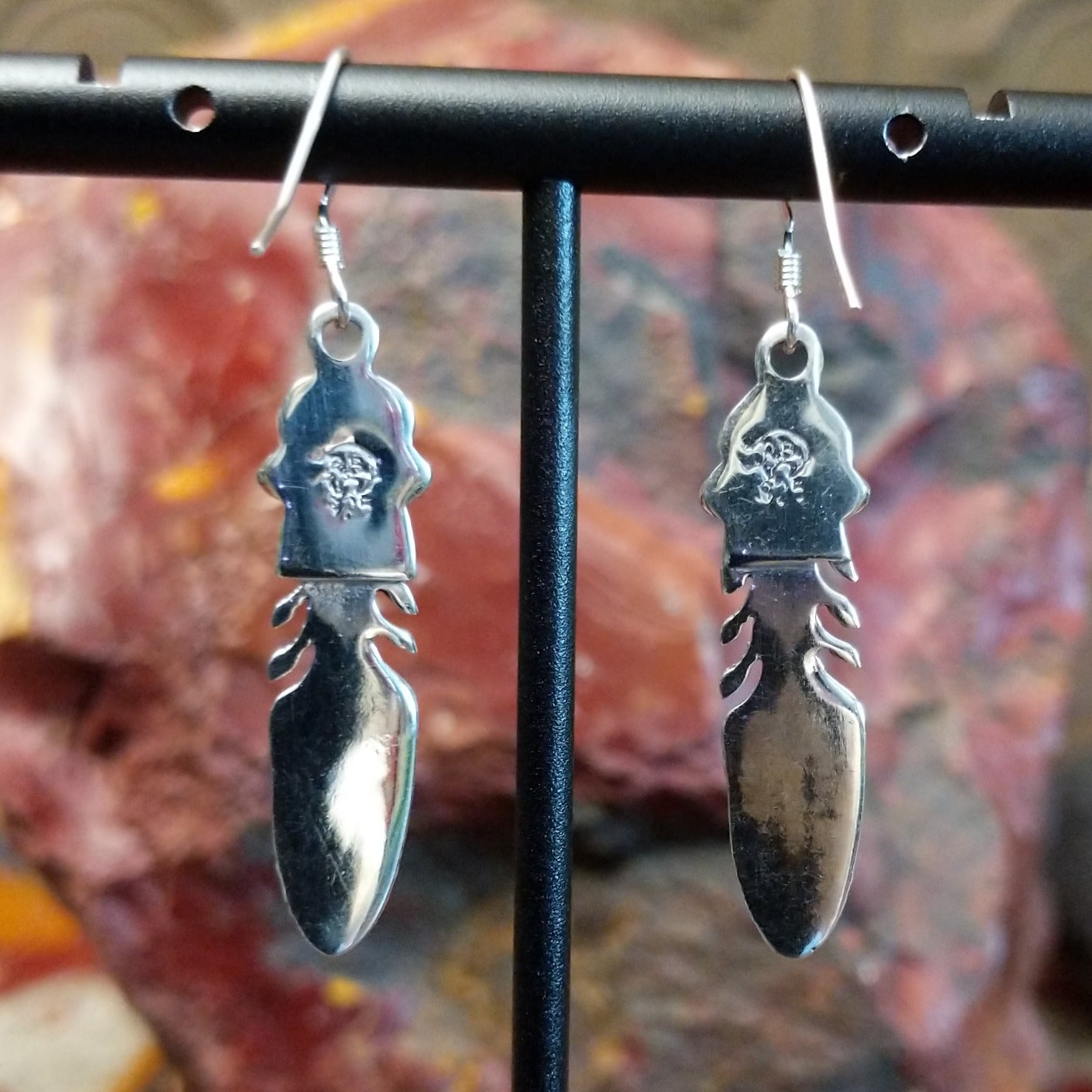 Sterling silver dangle feather earrings with coral set in notched bezels.