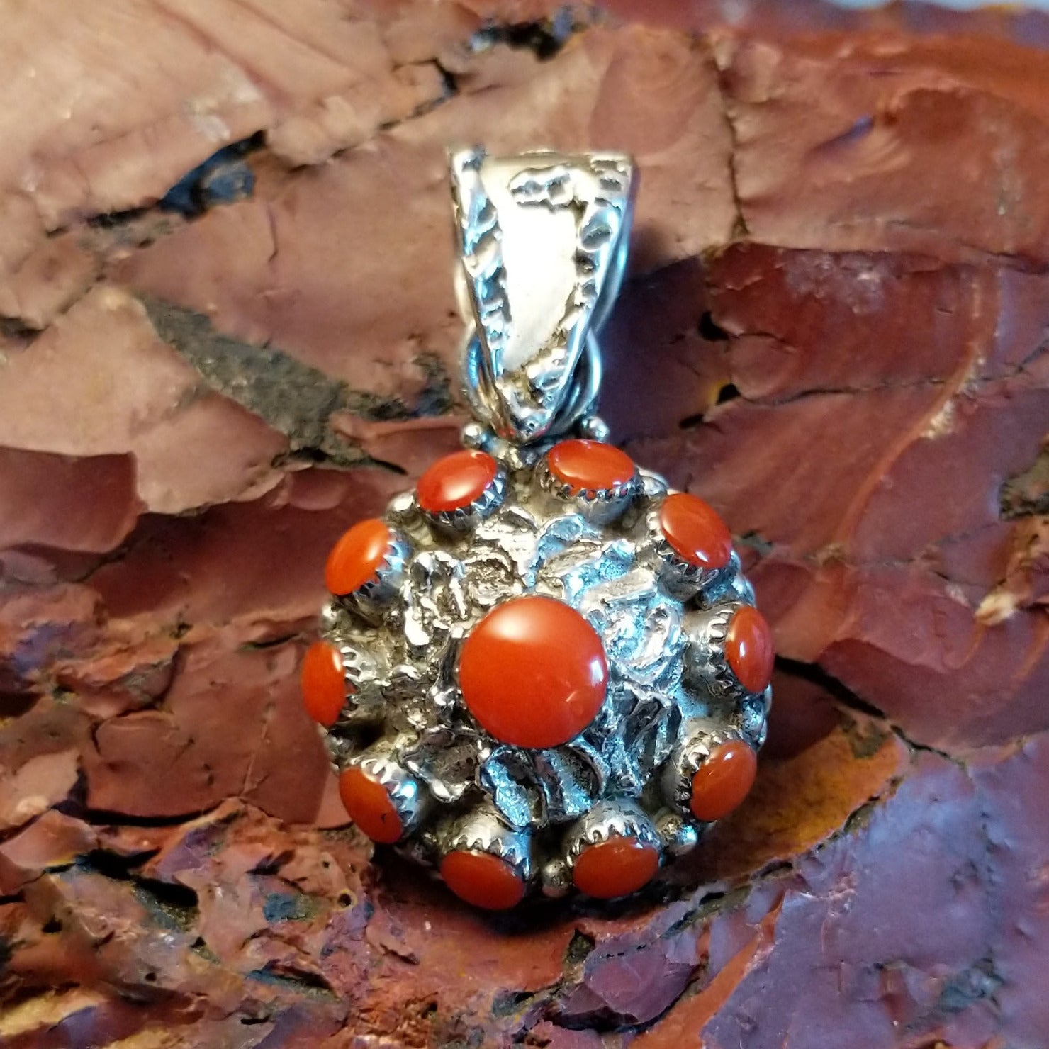 Sterling silver flower pendant with coral set in notched bezels and hammered finish.