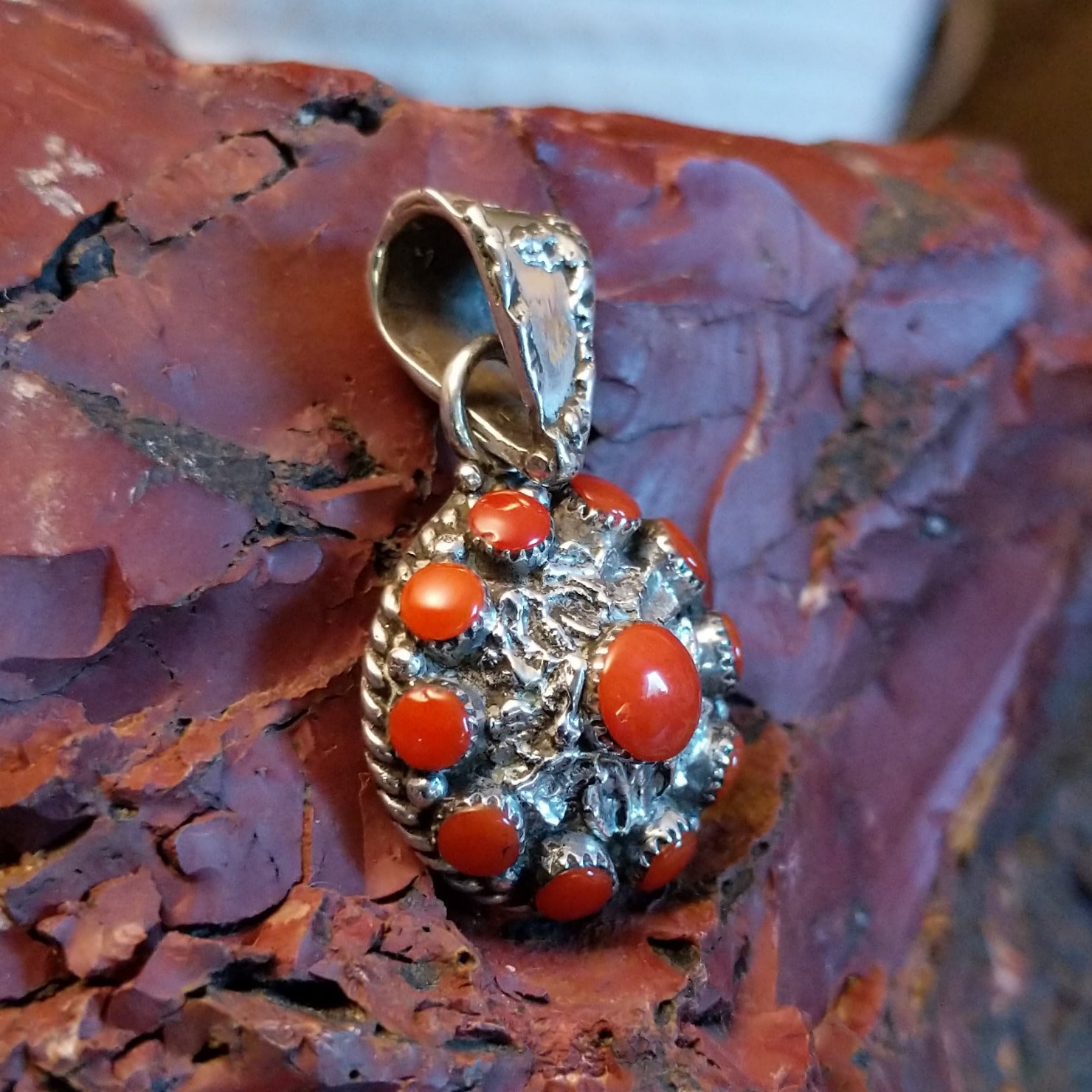 Sterling silver flower pendant with coral set in notched bezels and hammered finish.