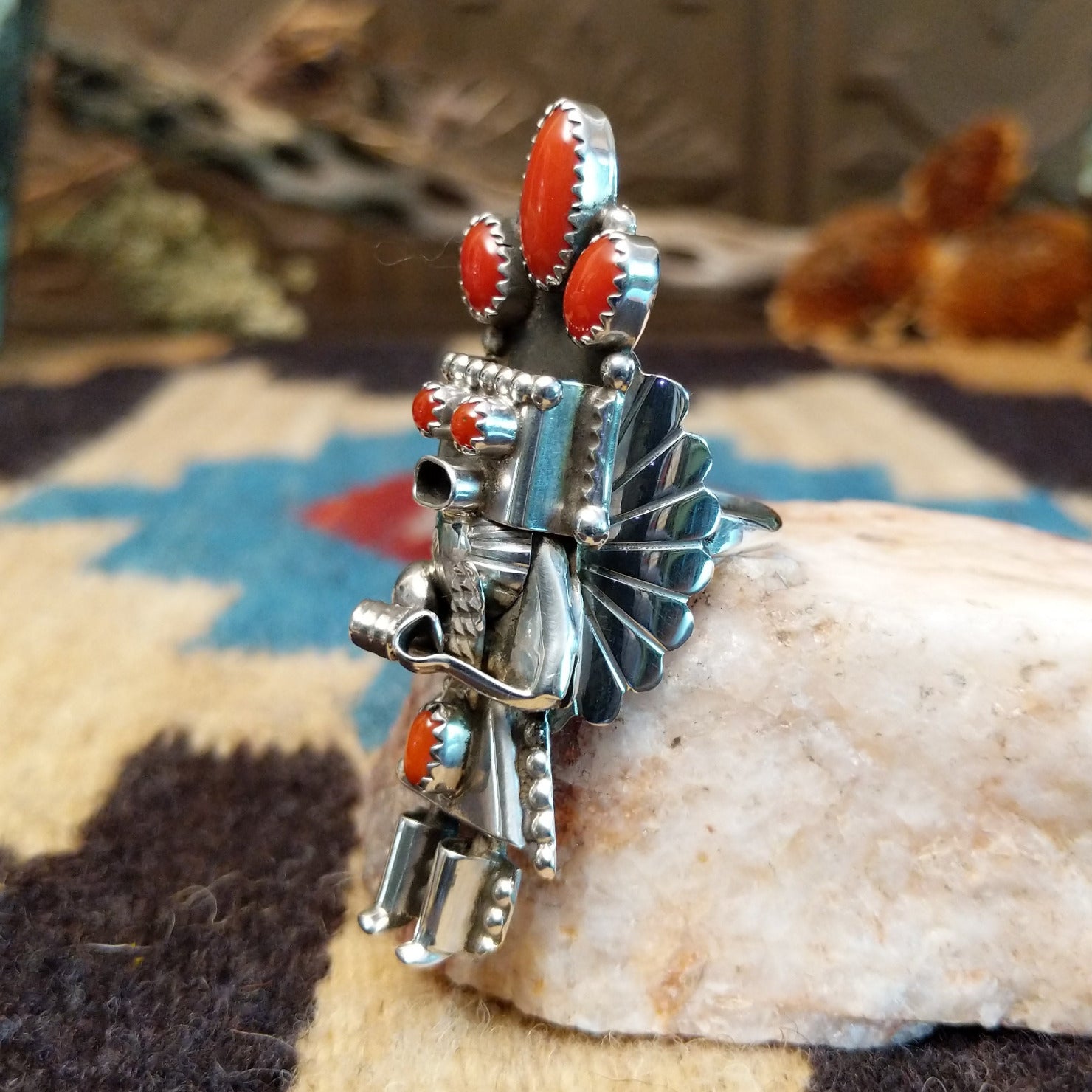 Sterling silver ring with kachina motif and coral set in bezels along the piece.