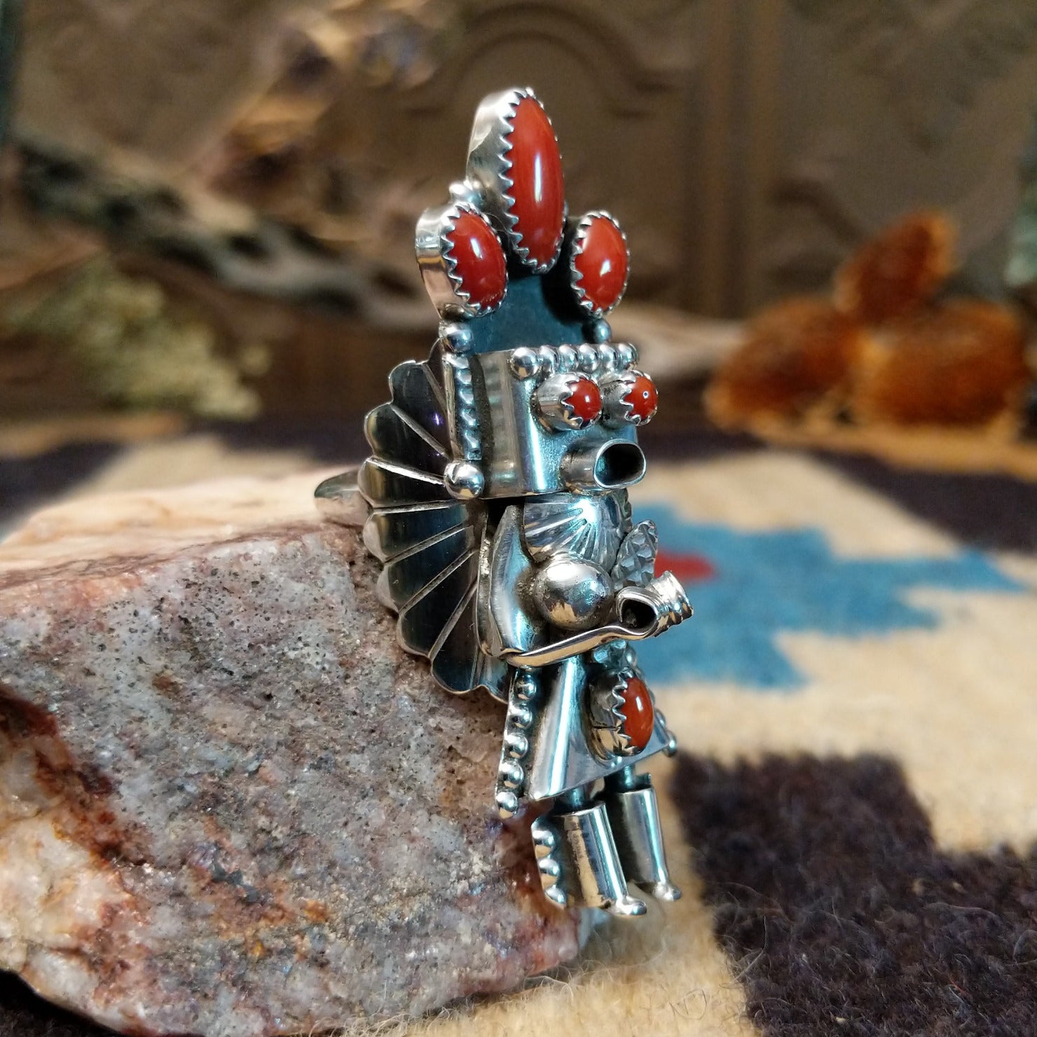 Sterling silver ring with kachina motif and coral set in bezels along the piece.