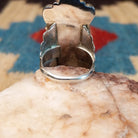 Sterling silver ring with kachina motif and coral set in bezels along the piece.