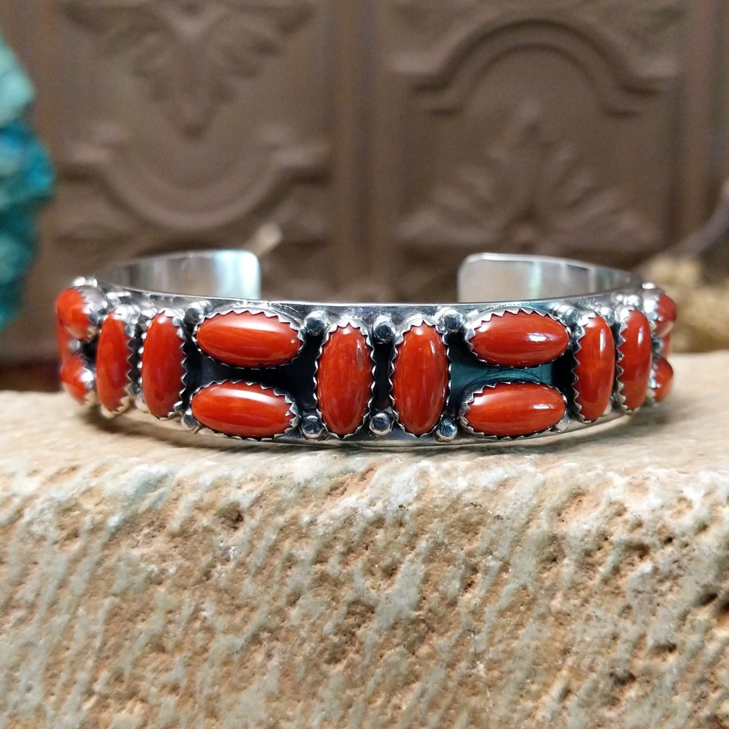 Sterling silver cuff bracelet with coral set in a parquet of oval bezels along the surface of the band.