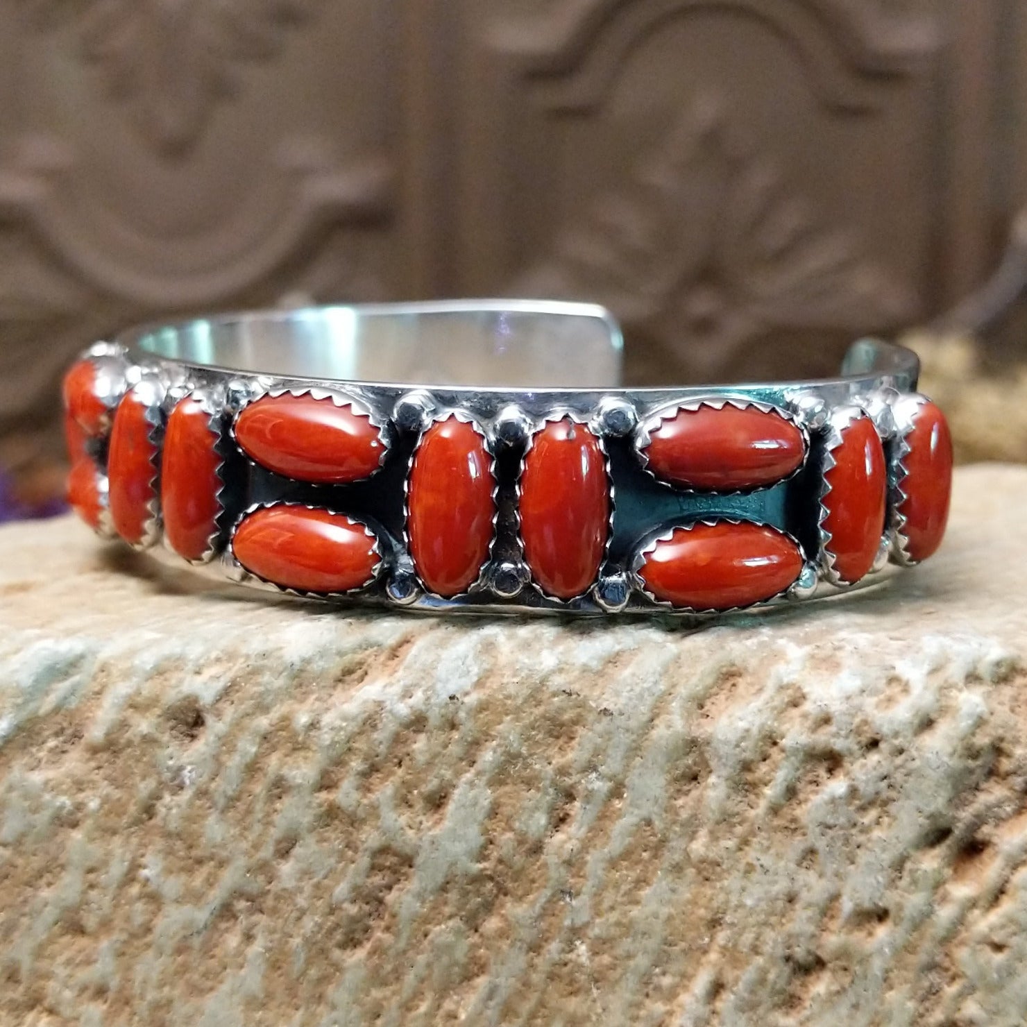 Sterling silver cuff bracelet with coral set in a parquet of oval bezels along the surface of the band.