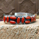Sterling silver cuff bracelet with coral set in a parquet of oval bezels along the surface of the band.