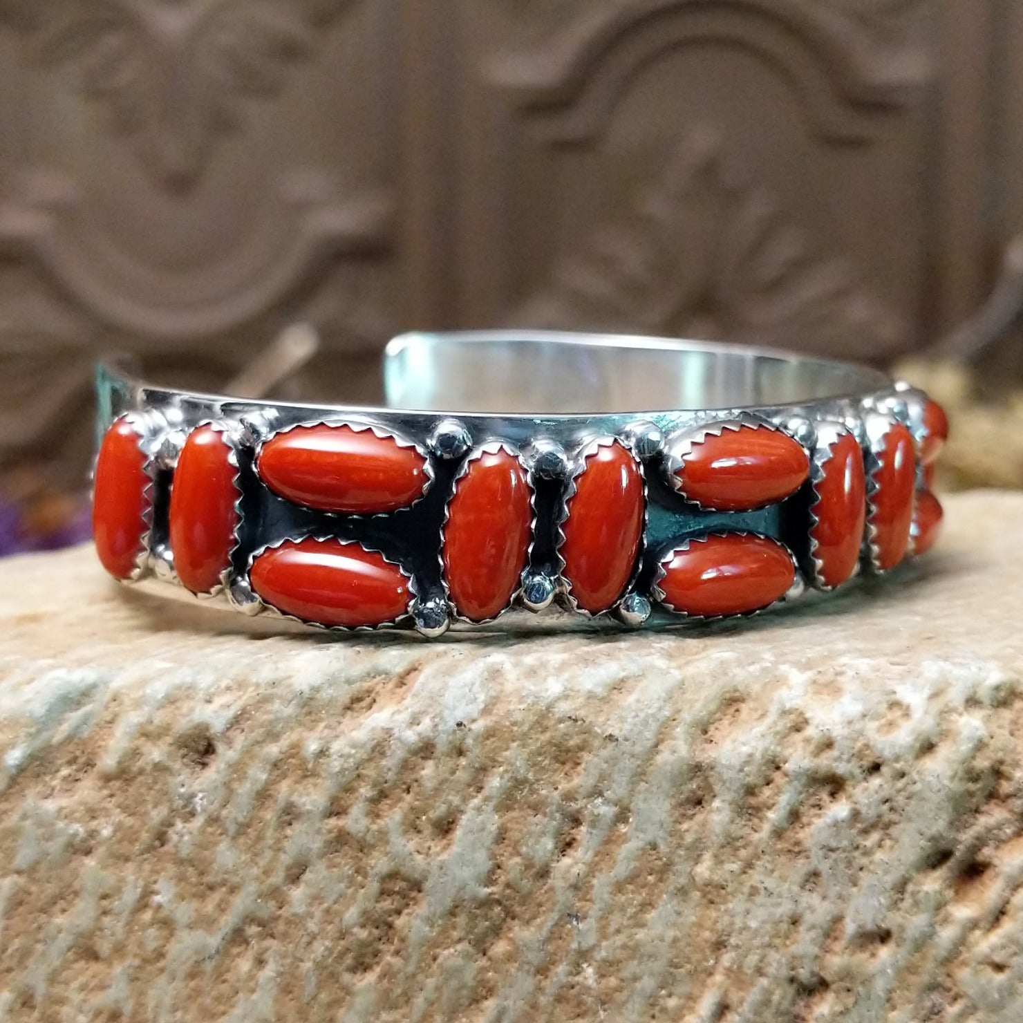 Sterling silver cuff bracelet with coral set in a parquet of oval bezels along the surface of the band.