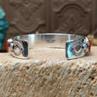 Sterling silver cuff bracelet with coral set in a parquet of oval bezels along the surface of the band.