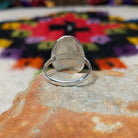 Striking Coral Ray Ring by Raymond Coriz featuring an oval red-orange coral stone framed by twisted sterling silver rope and radiating oxidized silver sunburst details; underside view.
