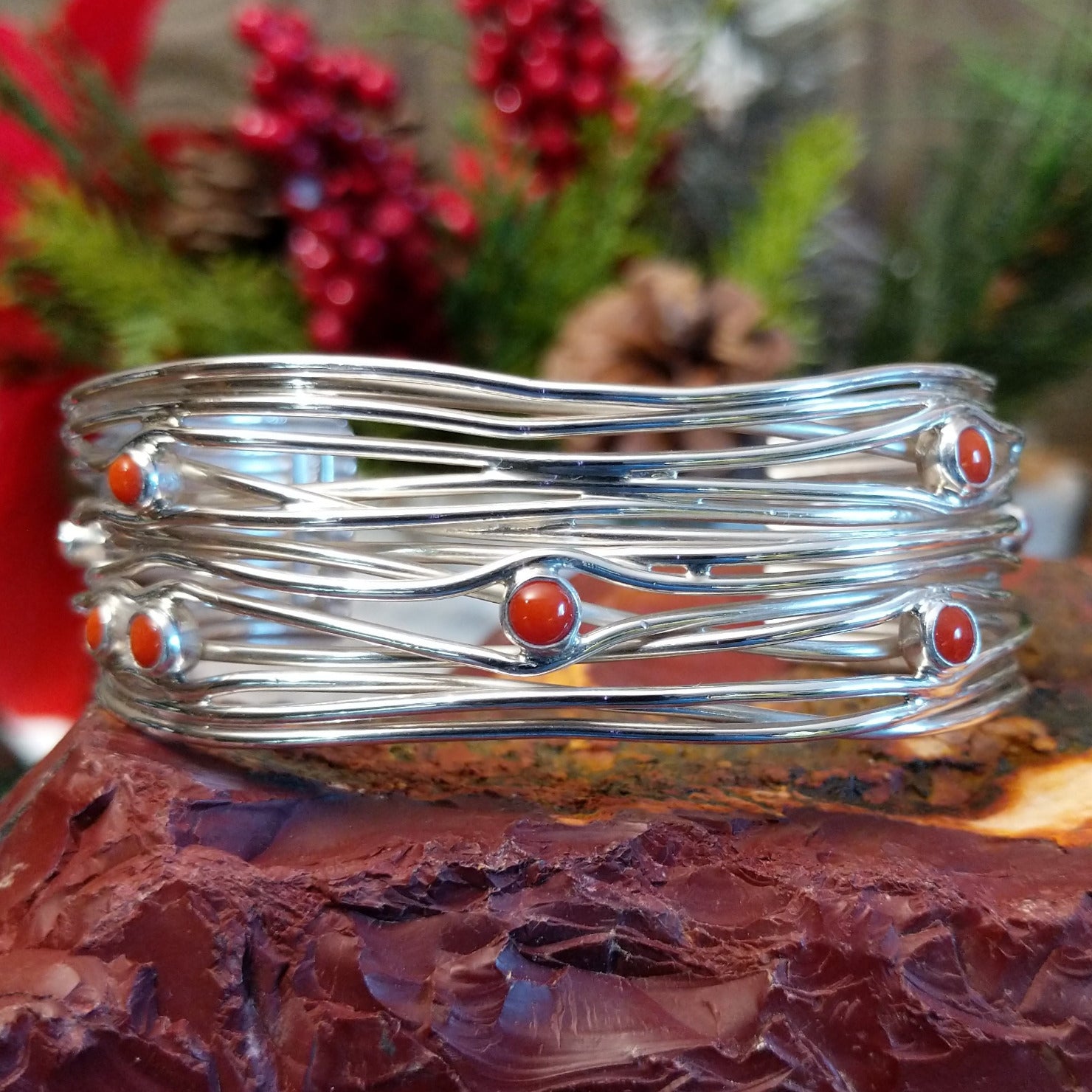 Strands of sterling silver creating the band of the cuff with scattered petite coral set in bezels.