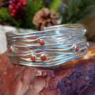 Strands of sterling silver creating the band of the cuff with scattered petite coral set in bezels.