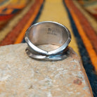 This striking Coral Trio Ring by Reed Charley features three rectangular red-orange coral stones in sawtooth silver bezels, accented by polished silver beads and a wide oxidized silver band; underside view.