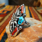 Coral & Turquoise Feather Ring by Jason Livingston featuring an oval turquoise stone, two elongated coral stones, intricate silver feather detailing, decorative scrollwork, polished silver beads, and stamped accents in an elaborate Southwestern design; side view.