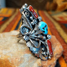 Coral & Turquoise Feather Ring by Jason Livingston featuring an oval turquoise stone, two elongated coral stones, intricate silver feather detailing, decorative scrollwork, polished silver beads, and stamped accents in an elaborate Southwestern design; side view.