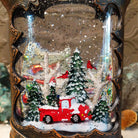Festive Cowboy Boot Truck Snow Globe featuring a red vintage pickup truck surrounded by snow-covered trees inside a dark brown Western boot with silver stars and concho detailing.