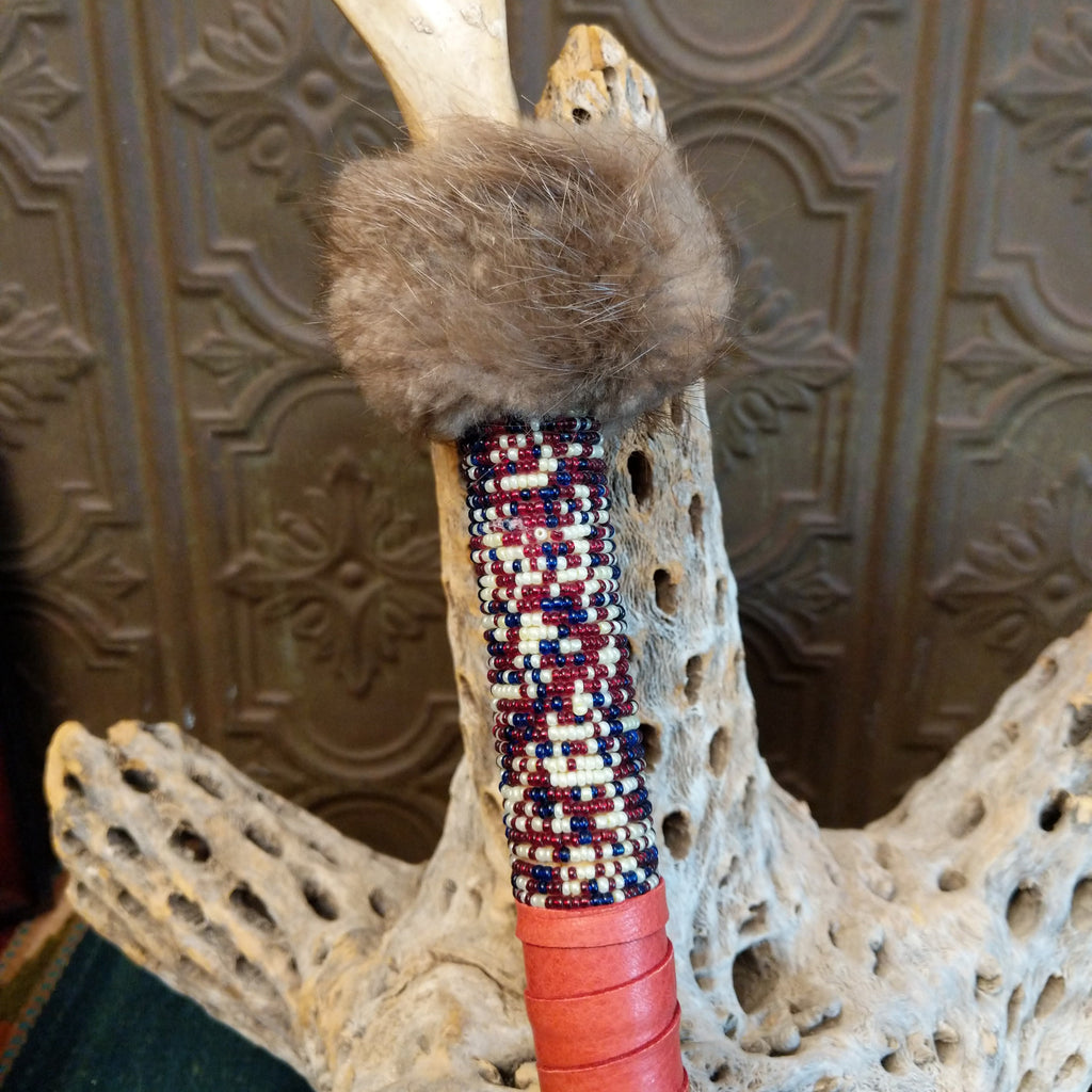 The top of the shaft is decorated with colorful beading, red leather, and fur.