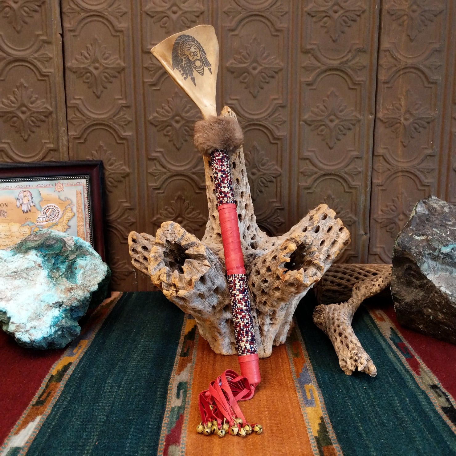 Deer shoulder blade engraved with headdress design on the top of the shaft that is decorated with colorful beading and red leather.