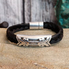 A braided black horsehair bracelet with an ornate crossed arrows accent and magnetic clasp.