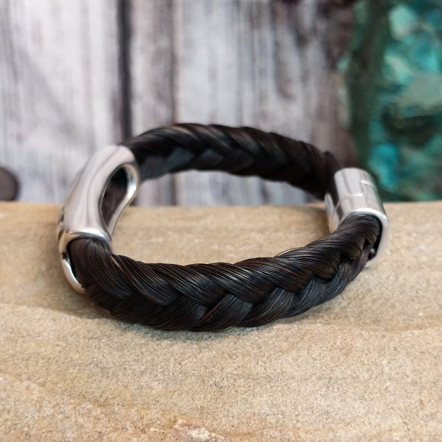 A braided black horsehair bracelet with an ornate crossed arrows accent and magnetic clasp.