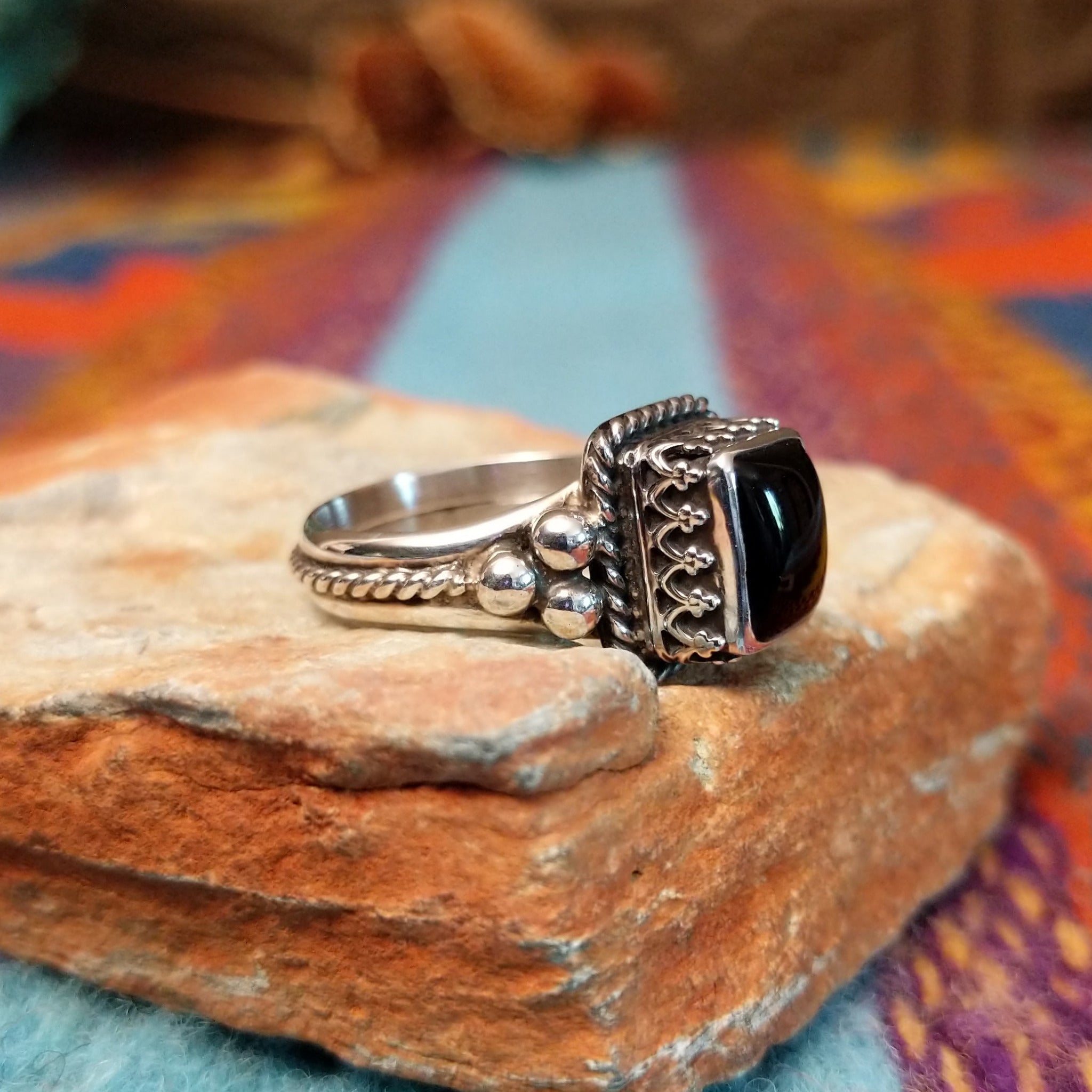 Black onyx silver ring by Angela Martin with twisted border and silver drop accents.