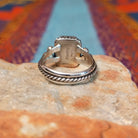 Black onyx silver ring by Angela Martin with twisted border and silver drop accents.