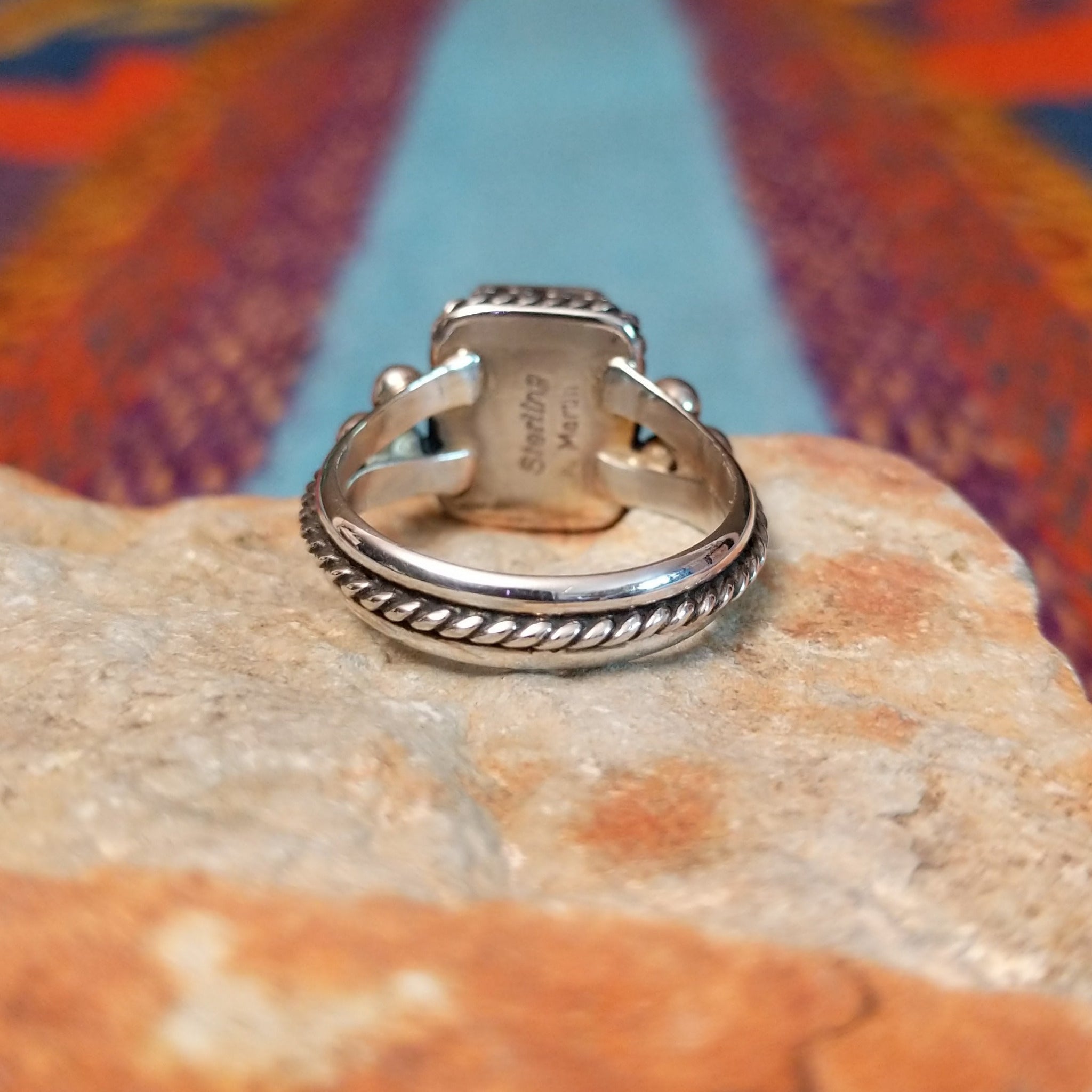 Black onyx silver ring by Angela Martin with twisted border and silver drop accents.