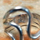 Handcrafted sterling silver ring by Raymond Coriz featuring a polished openwork design with flowing curved silver forms and a contemporary sculptural style; artisan and Sterling Silver stamp.