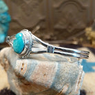 Sterling silver bracelet with turquoise set in an oval bezel, framed by twisted rope and an incised setting.