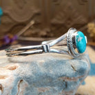 Sterling silver bracelet with turquoise set in an oval bezel, framed by twisted rope and an incised setting.