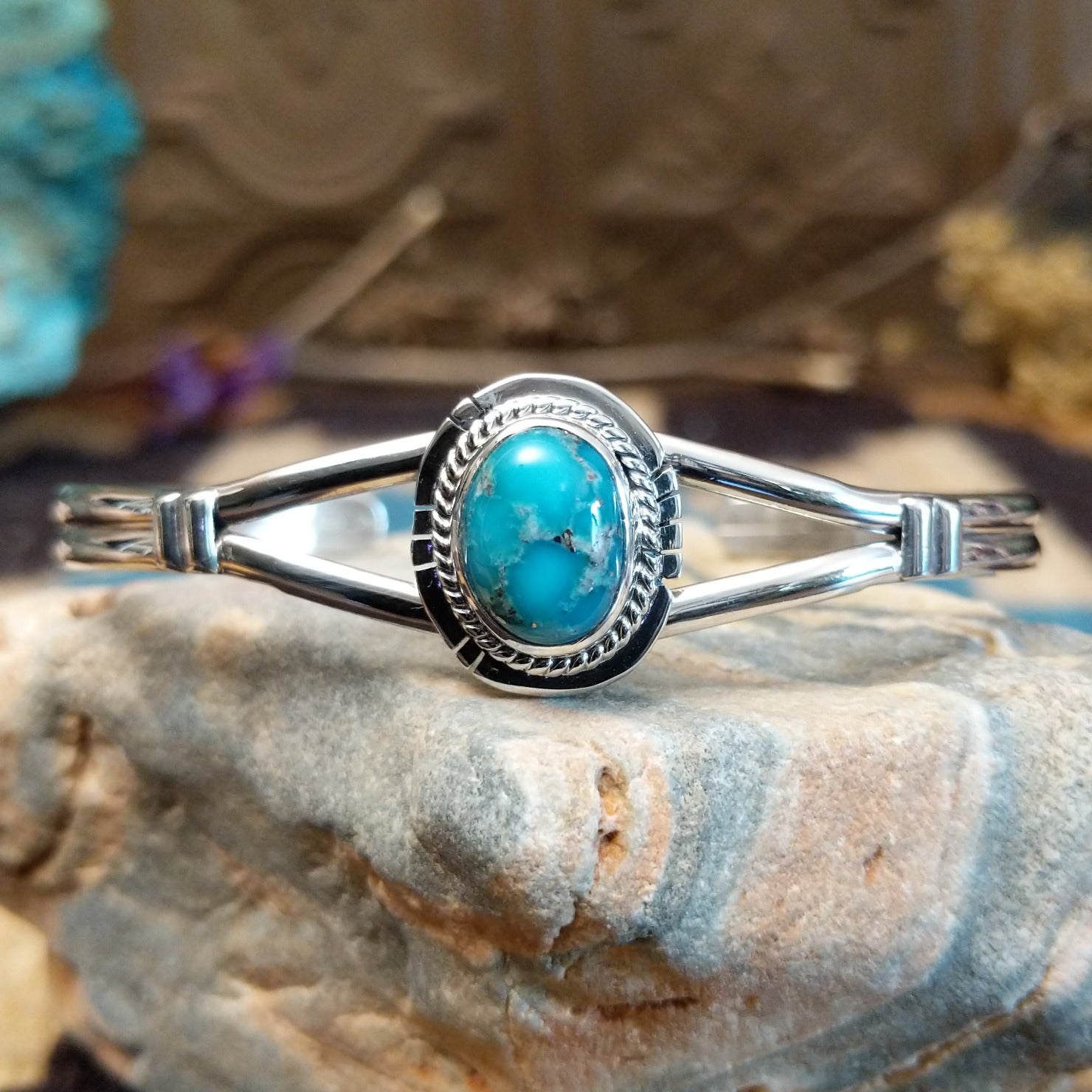 Sterling silver bracelet with turquoise set in an oval bezel, framed by twisted rope and incised accents.