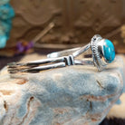 Sterling silver bracelet with turquoise set in an oval bezel, framed by twisted rope and incised accents.