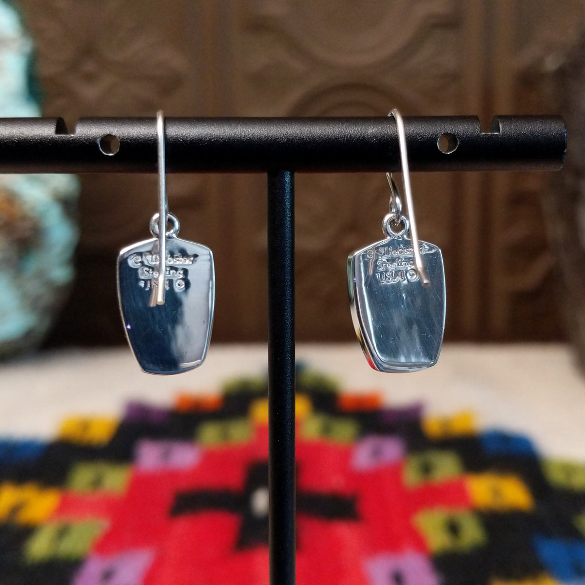 Denim Lapis Earrings by Cathy Webster featuring polished blue stones with cloudy light-blue and white variations, set in smooth silver bezels and suspended from French ear wires; artisan and Sterling Silver stamp.