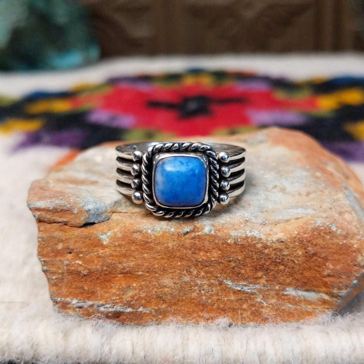 Denim lapis ring by Raymond Coriz with square stone, twisted silver border, and four-row band.