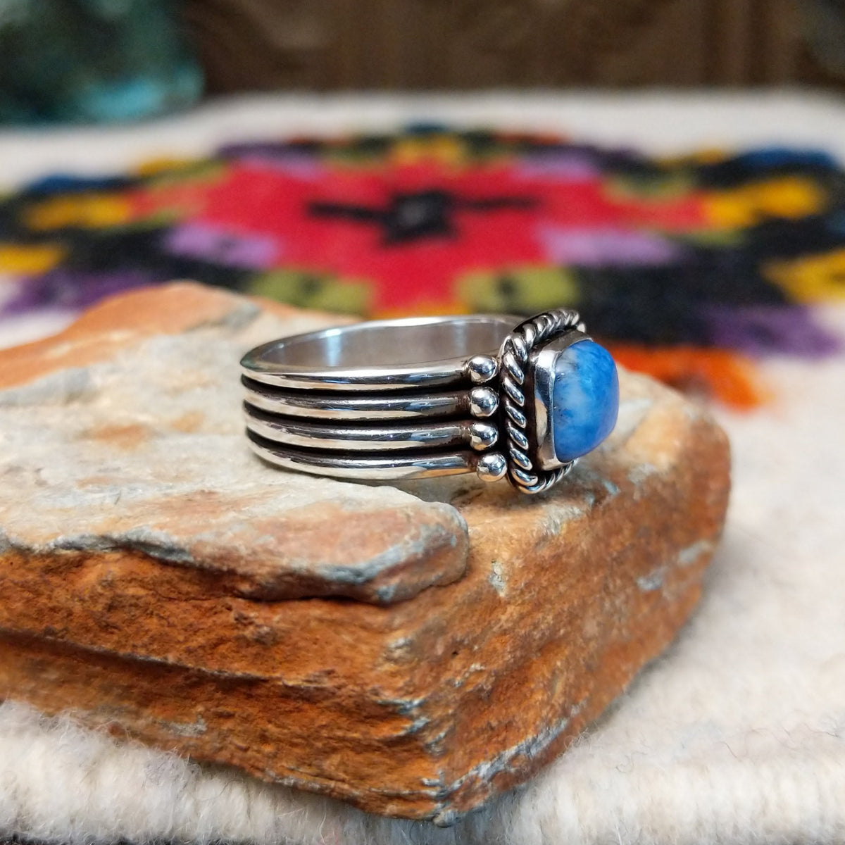 Denim lapis ring by Raymond Coriz with square stone, twisted silver border, and four-row band.