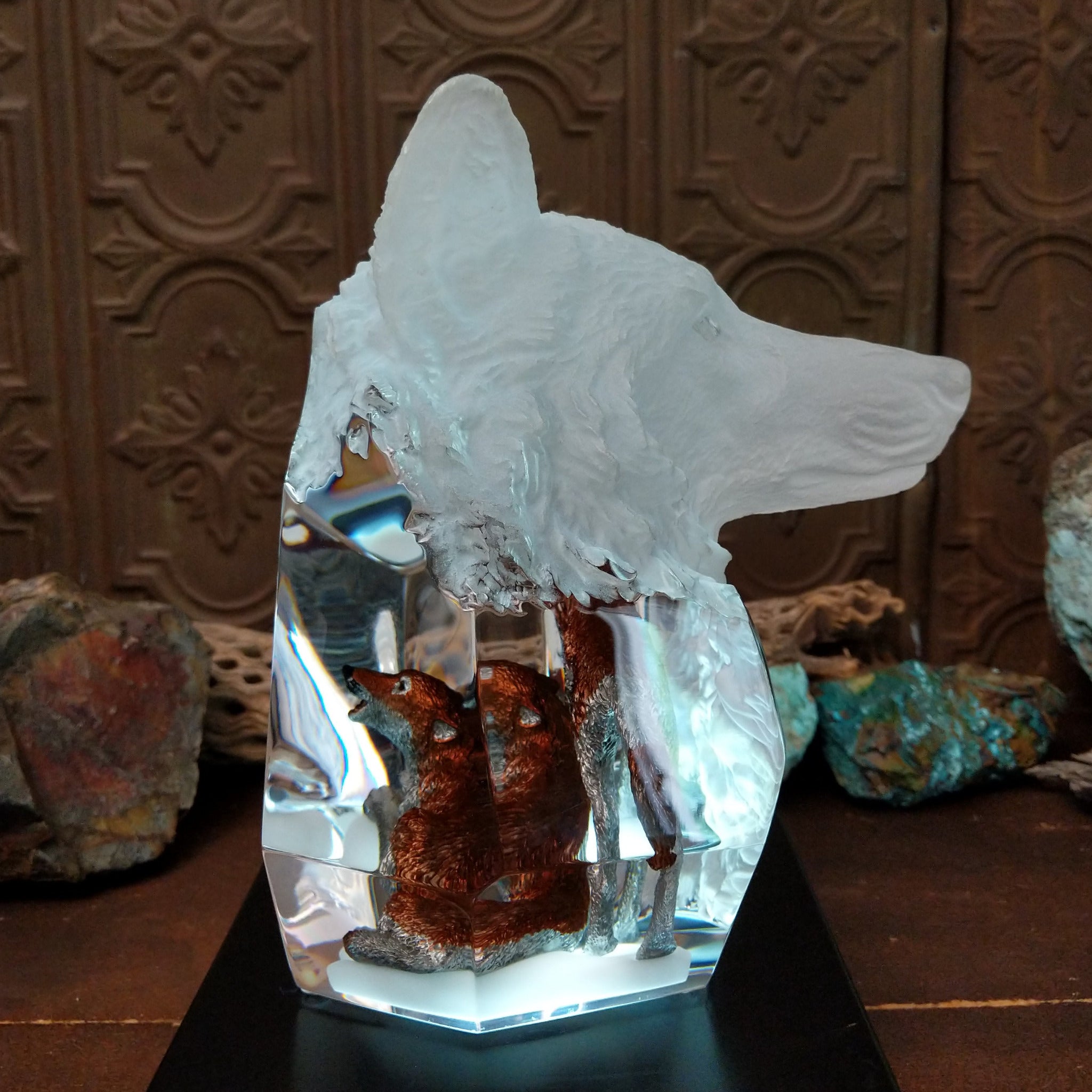 A clear Lucite sculpture featuring two hand-painted wolves with a frosted wolf's face emerging in the background, symbolizing loyalty and family; lower light display.