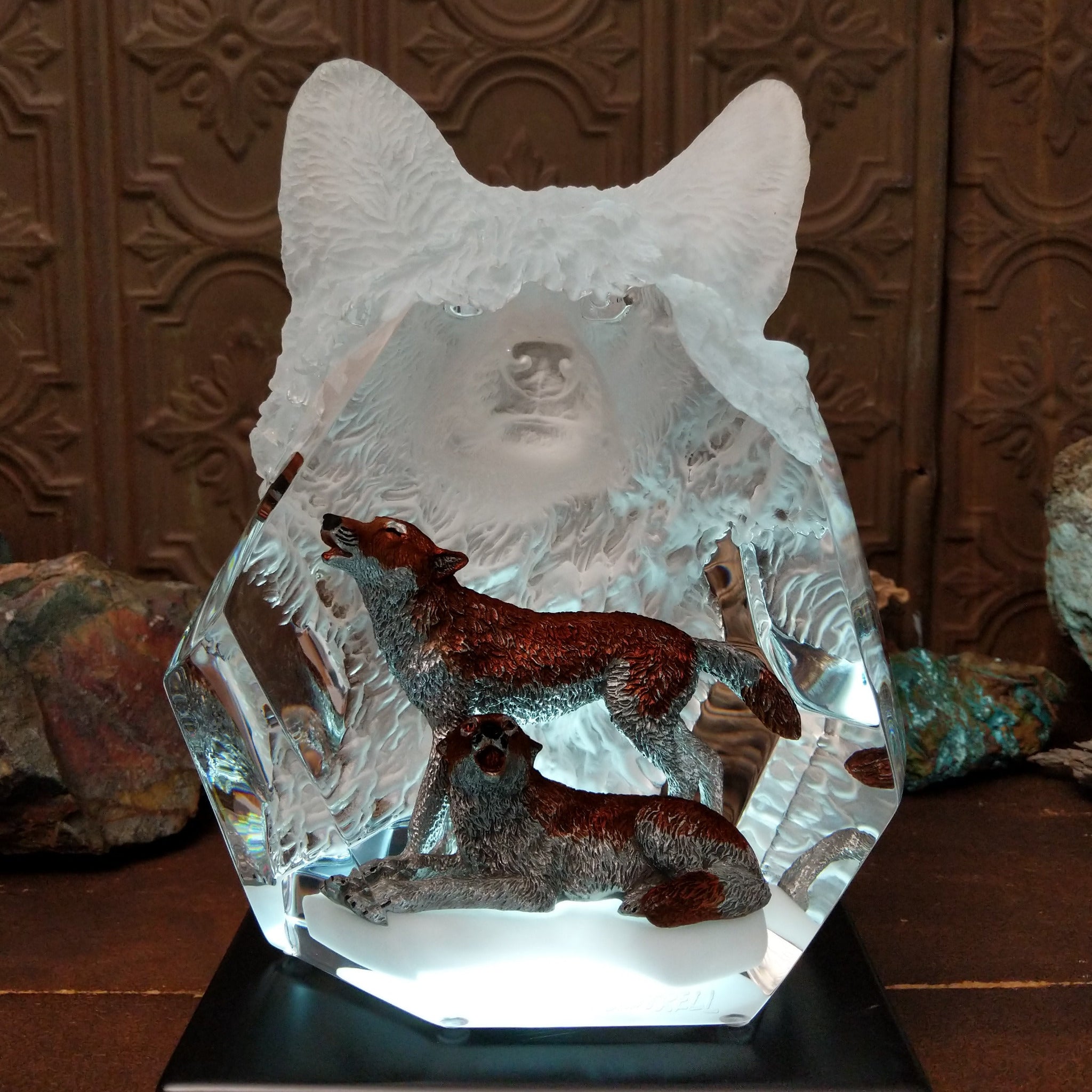 A clear Lucite sculpture featuring two hand-painted wolves with a frosted wolf's face emerging in the background, symbolizing loyalty and family; lower light display.