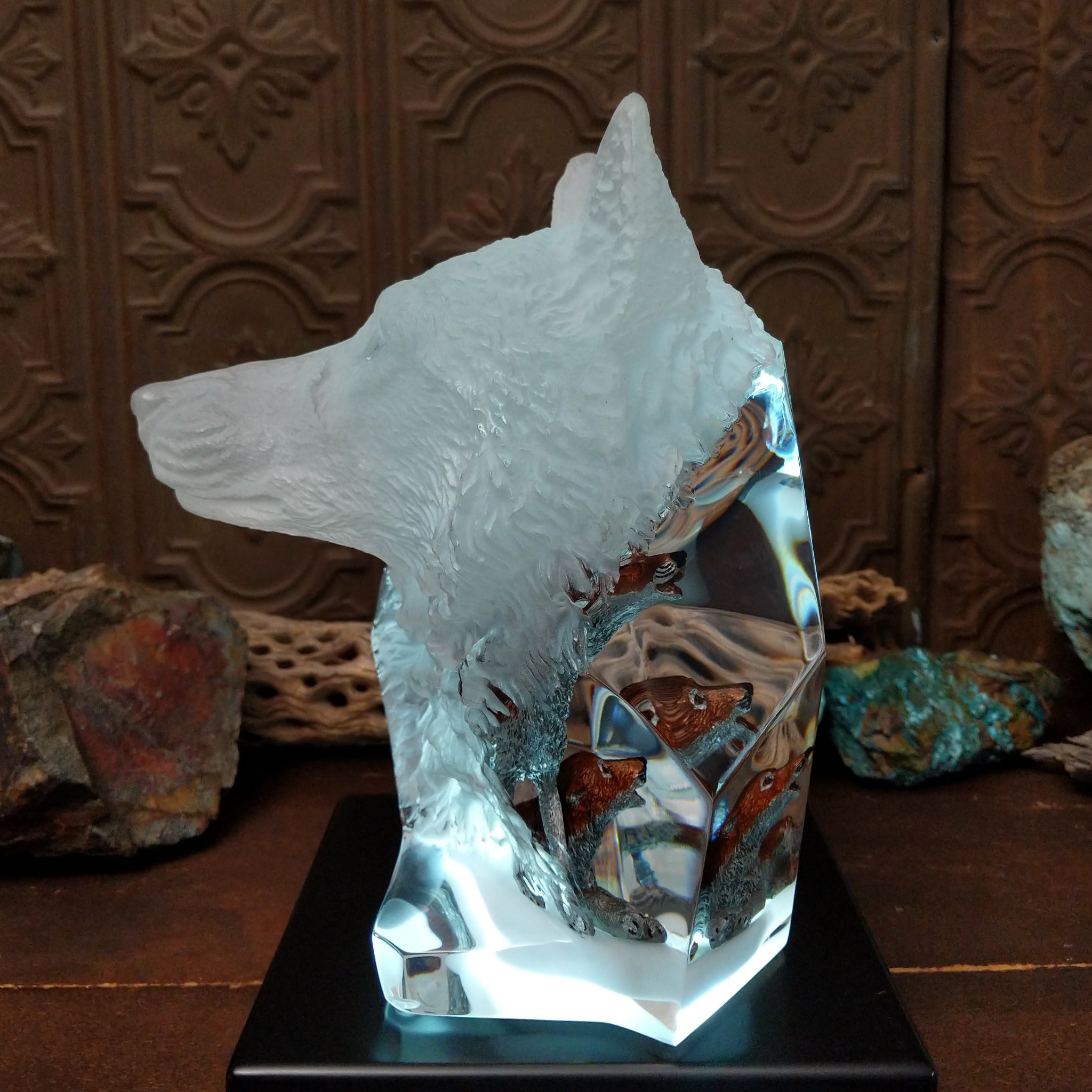 A clear Lucite sculpture featuring two hand-painted wolves with a frosted wolf's face emerging in the background, symbolizing loyalty and family; lower light display.