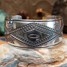 Wide sterling silver cuff bracelet with raised geometric silverwork, hand-stamped details, and oxidized accents.