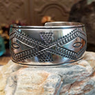 Wide sterling silver cuff bracelet with raised geometric silverwork, hand-stamped details, and oxidized accents.