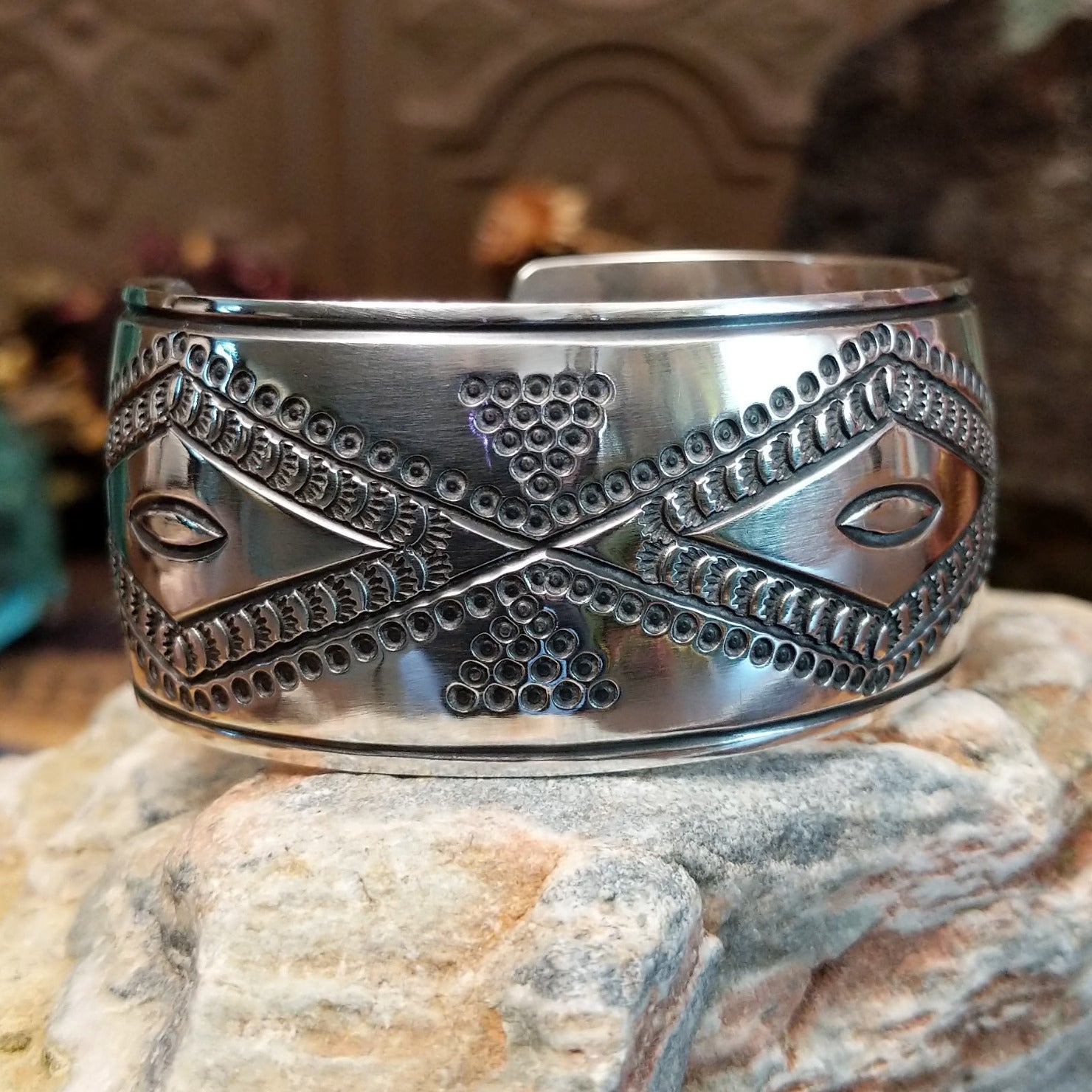 Wide sterling silver cuff bracelet with raised geometric silverwork, hand-stamped details, and oxidized accents.