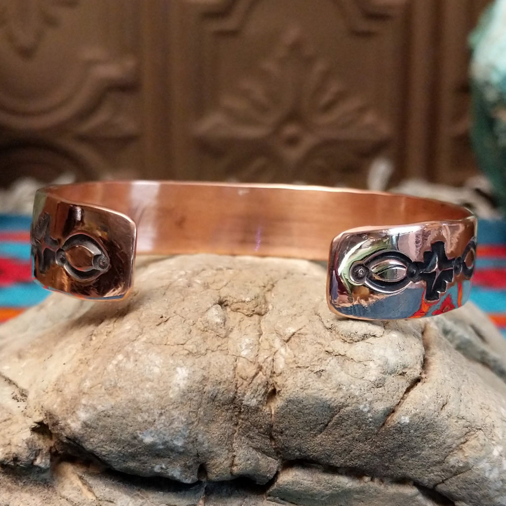 Copper cuff bracelet with sterling silver inlaid featuring shrub-like details.