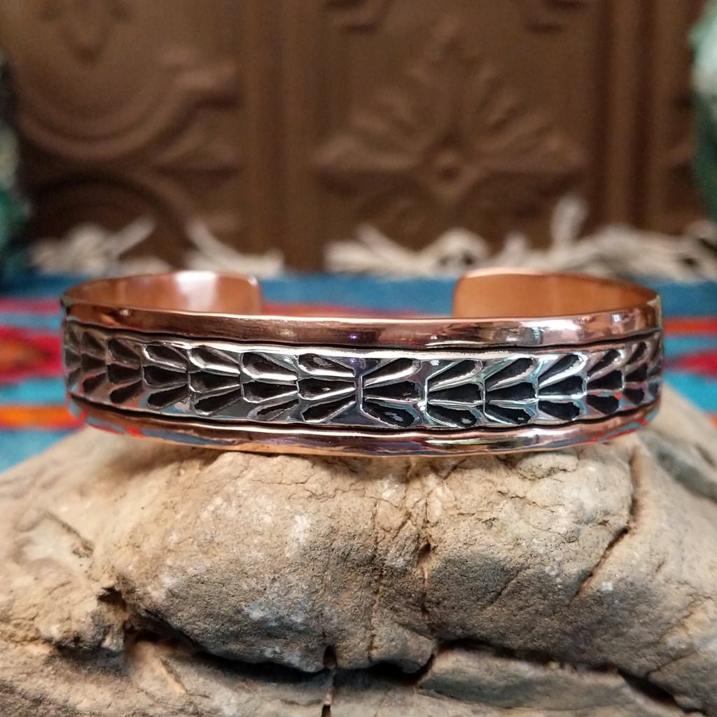 Copper cuff bracelet with sterling silver inlaid featuring shrub-like details.