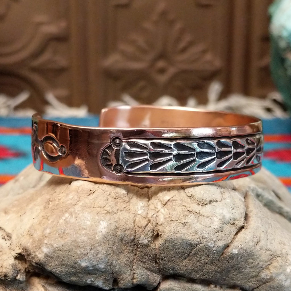 Copper cuff bracelet with sterling silver inlaid featuring shrub-like details.