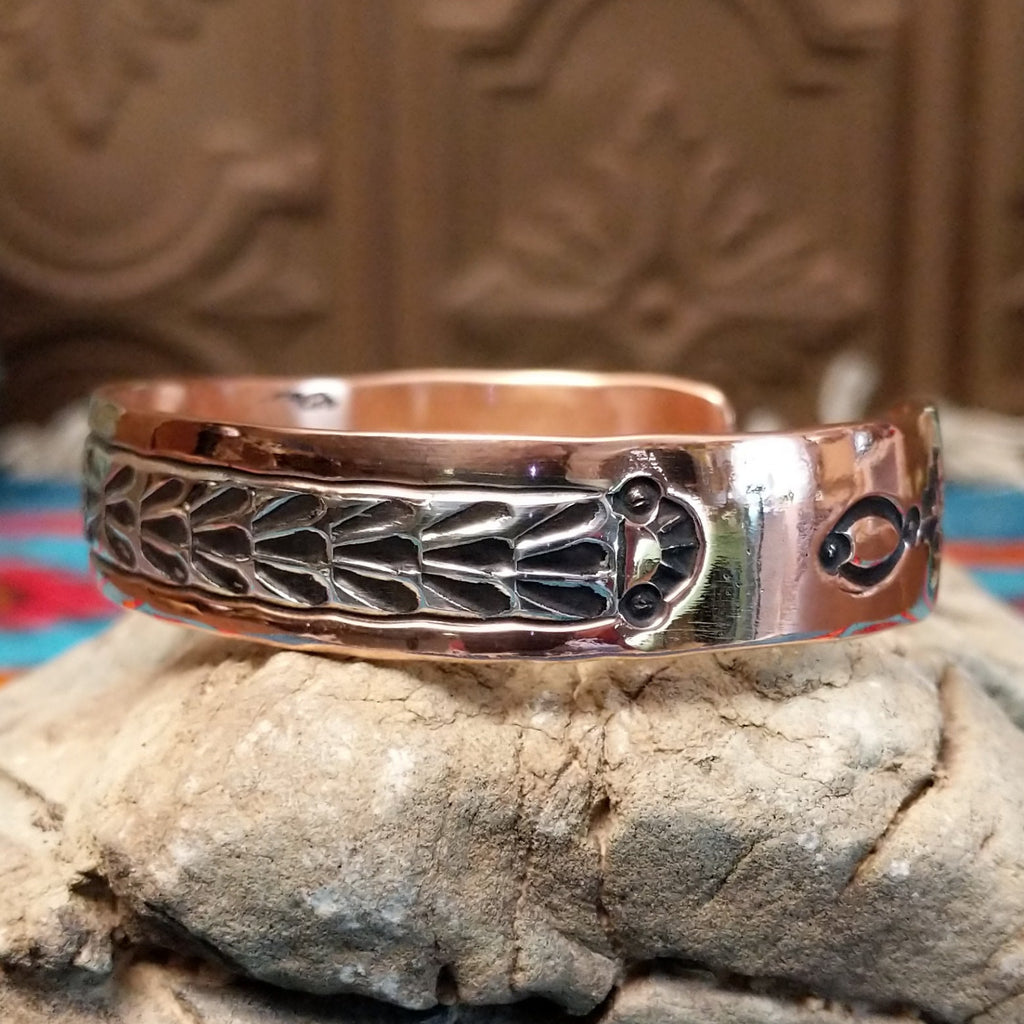 Copper cuff bracelet with sterling silver inlaid featuring shrub-like details.