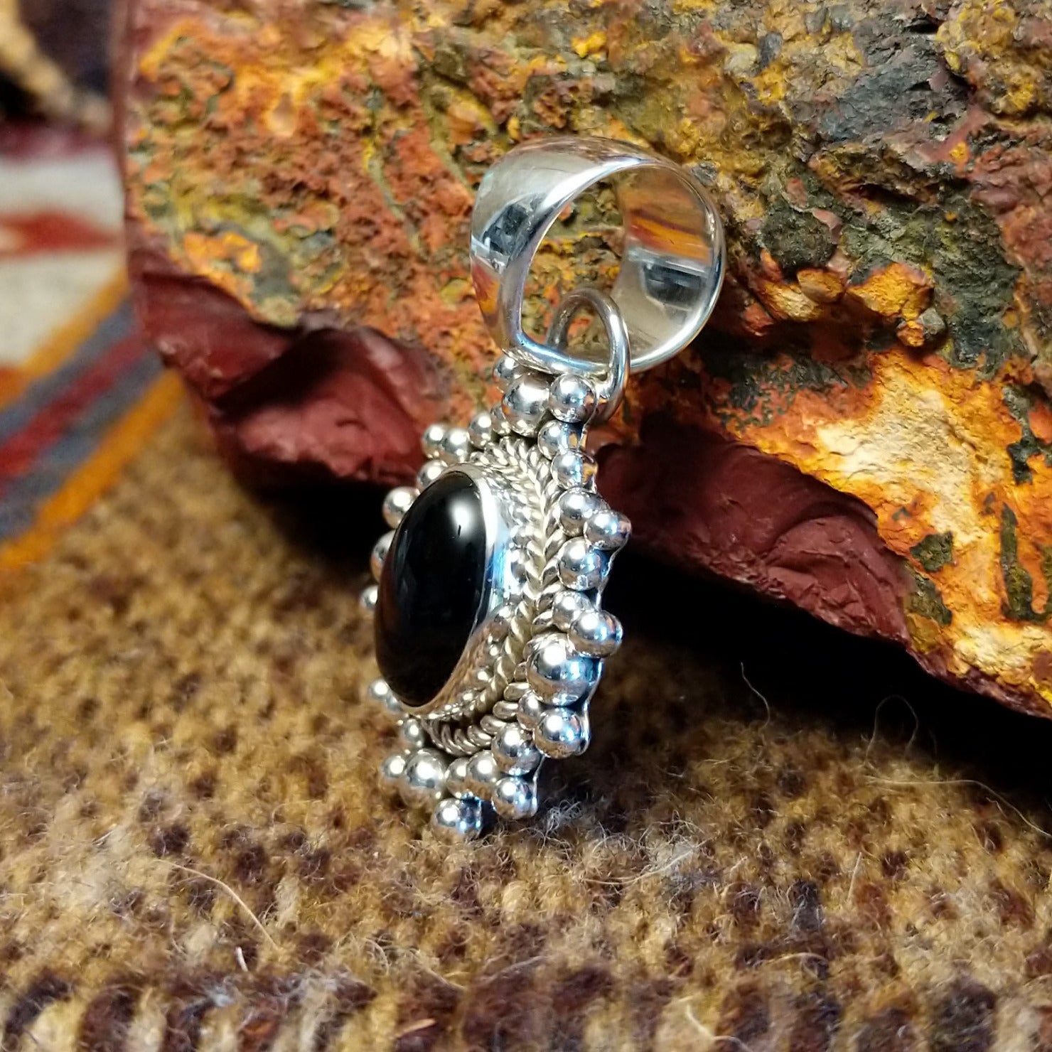 Sterling silver and black onyx pendant framed by dotted accents and a twisted rope design.