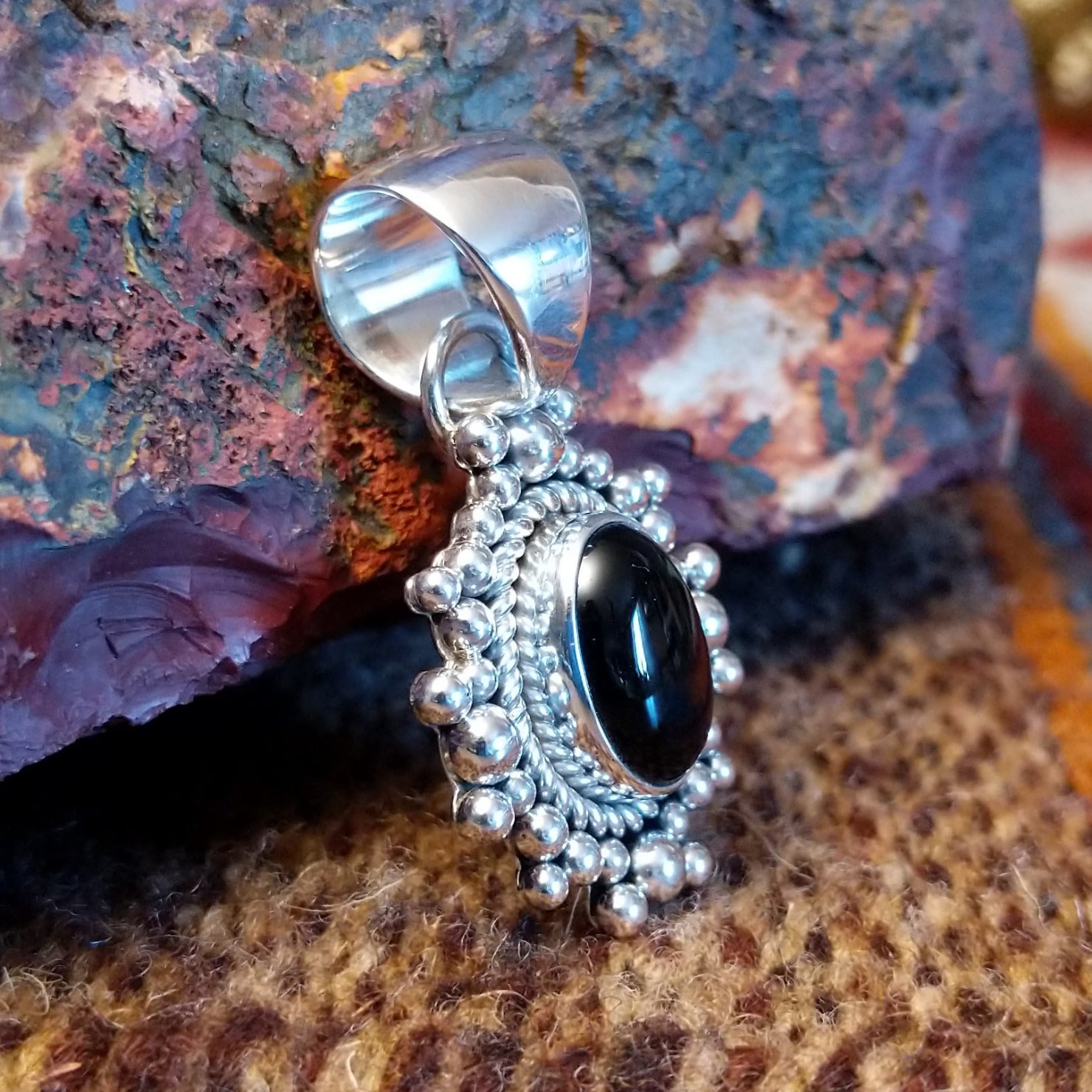 Sterling silver and black onyx pendant framed by dotted accents and a twisted rope design.