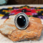 This Black Onyx Ring by J. Frank features a large oval black onyx stone set in sterling silver with twisted rope detailing and a raised beaded border.