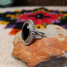 This Black Onyx Ring by J. Frank features a large oval black onyx stone set in sterling silver with twisted rope detailing and a raised beaded border; side view.